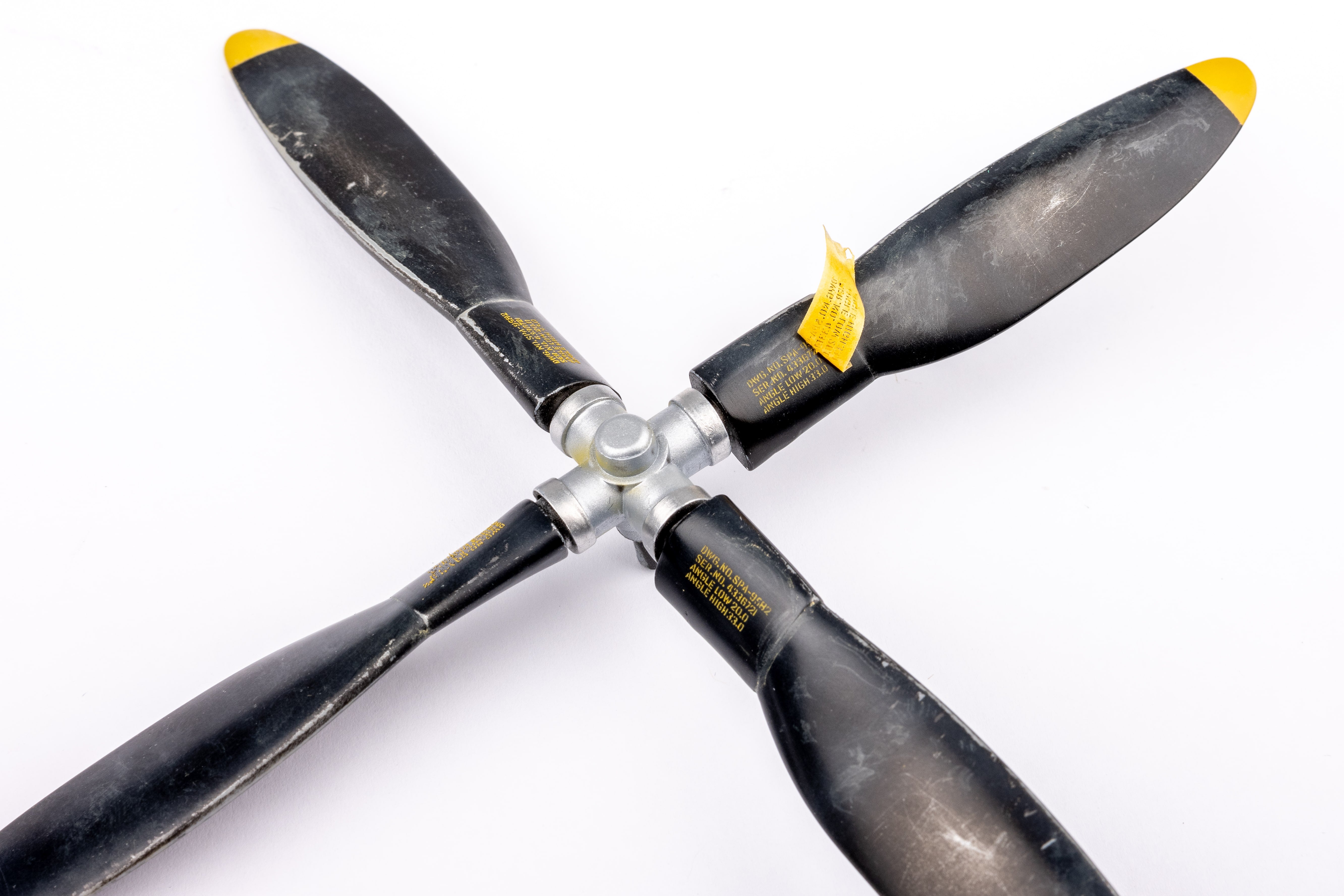 白背景で撮影された、黒と黄色の塗装が施された第二次世界大戦時代の航空機プロペラのクローズアップ